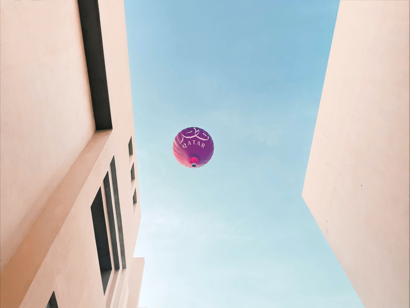 a purple balloon flying in the air between two buildings